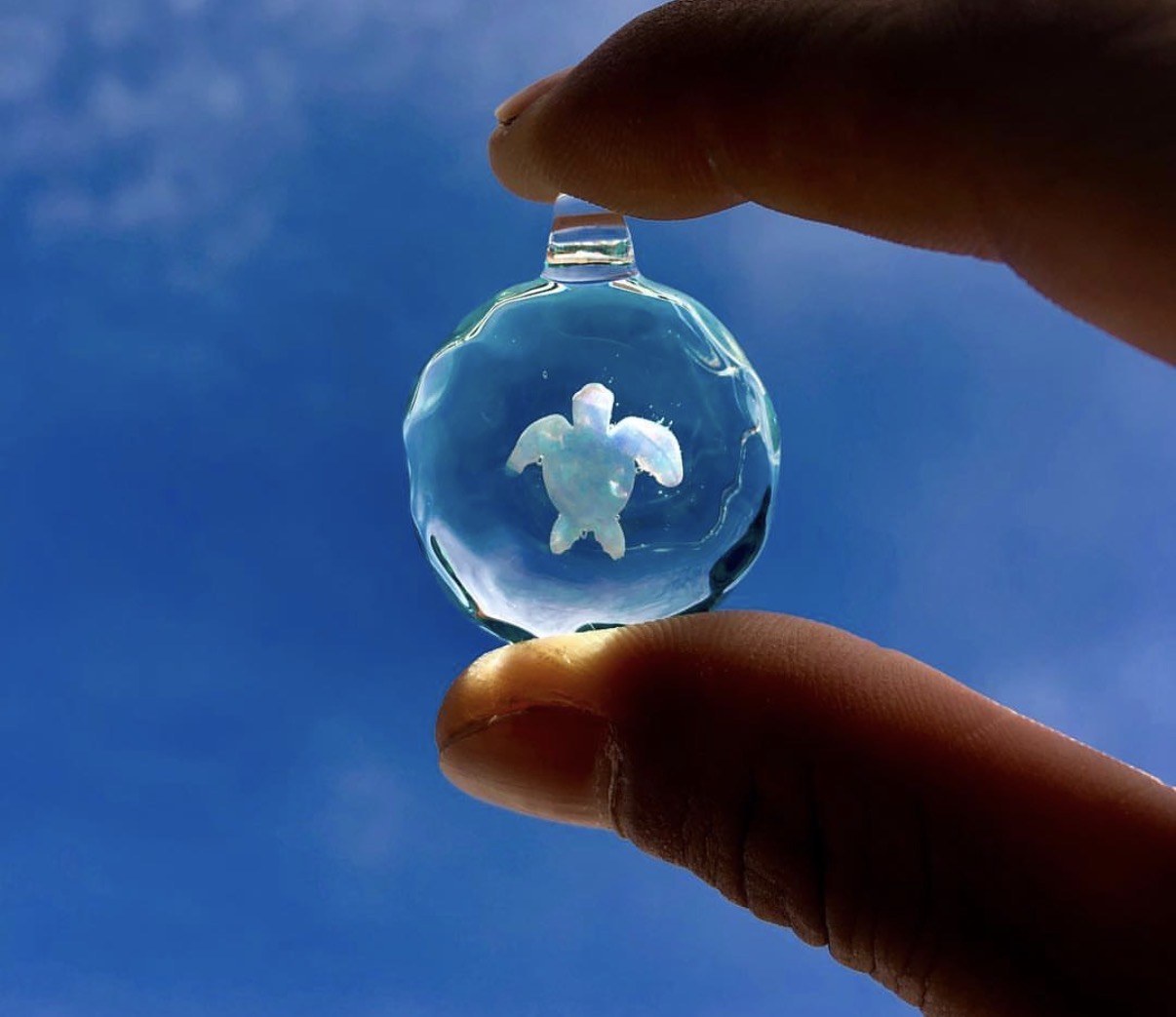 Clear blue glass piece held up to Miyakojima sky